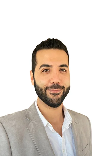 A man with beard and suit jacket smiling for the camera.