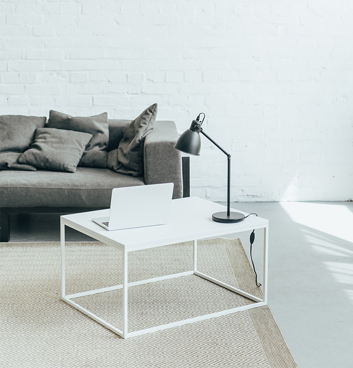 A laptop on top of a table in front of a couch.